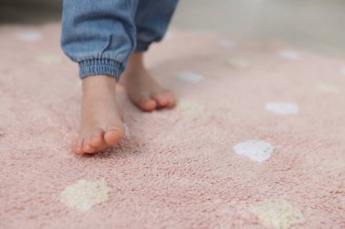 Evdeki yumuşak halıda yürüyen kız, yakın plan. Metin için boşluk