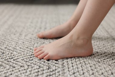 Evdeki gri halıdaki kız, yakın plan.