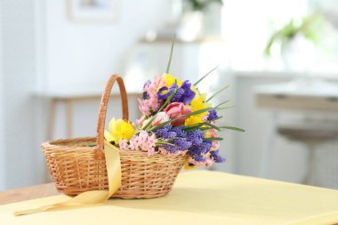 İçerideki masada güzel çiçekler olan hasır sepet.
