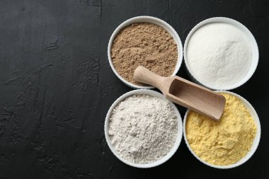 Kâselerdeki farklı un türleri ve siyah desenli masa, üst manzara. Metin için boşluk