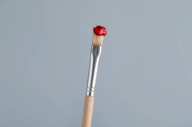 Açık gri arkaplanda kırmızı boyalı fırça, yakın plan