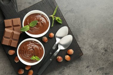Lezzetli çikolata, parçalar, nane ve fındıklar gri desenli masa, üst manzara. Metin için boşluk
