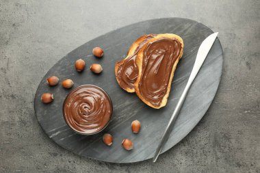 Lezzetli çikolatalı tostlar ve gri desenli masada fındıklar.