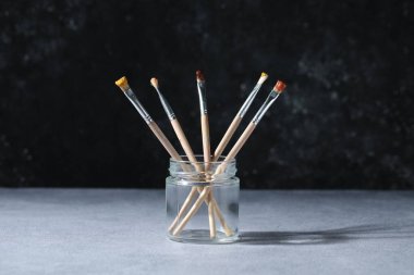 Gri masadaki kavanozda renkli fırçalar