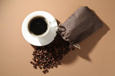 Kahve fincanda, fasulye bej arka planda, düz yerde.