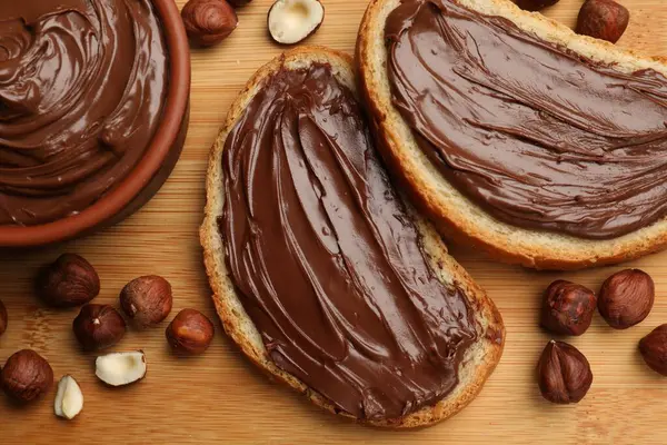 Lezzetli çikolatalı fındıklı tostlar ahşap masada fındıklar, düz yatış.