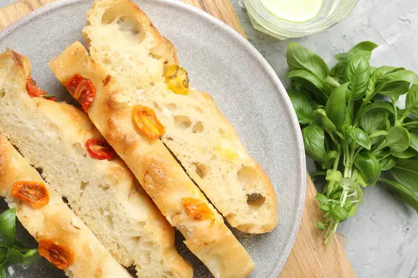Domatesli ve fesleğenli lezzetli Focaccia parçaları gri desenli masa, düz yatıyordu.