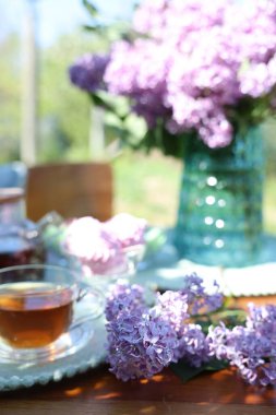 Bahçedeki masada güzel leylak çiçekleri ve çay, yakın plan.
