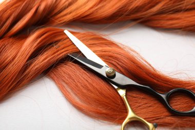 Hafif arkaplanda saç teli ve makas, yakın plan.