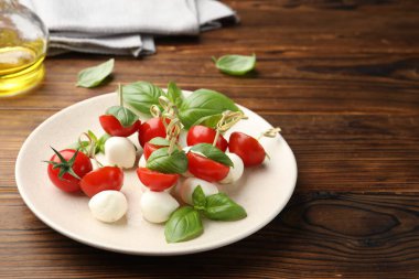 Ahşap masada mozzarella, domates ve fesleğen ile aperatifler.