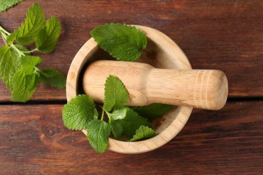 Taze limon merhemi yaprakları, ahşap masa üzerinde tokmak ve harç, düz uzanma