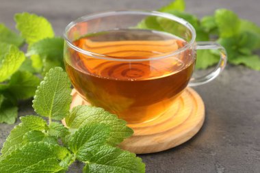 Cam bardakta Aromatik limon merhemi çayı ve gri desenli masada taze yapraklar, yakın plan.