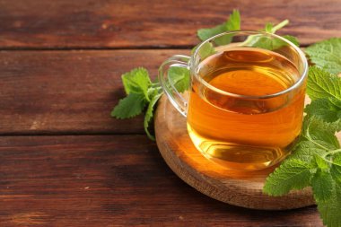 Cam bardakta Aromatik limon merhemi çayı ve ahşap masada taze yapraklar, yakın plan. Metin için boşluk