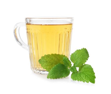 Cam bardakta Aromatik limon merhemi çayı ve beyaz bardakta taze yapraklar.