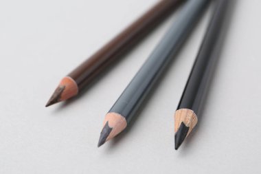 Açık arkaplanda üç farklı kaş kalemi, yakın plan.