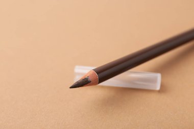 Bej arka planda kahverengi kaş kalemi, yakın plan. Metin için boşluk