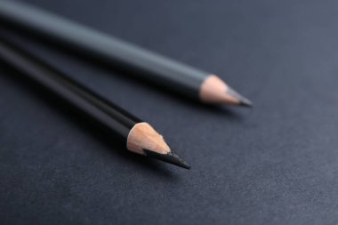 Koyu arkaplanda iki farklı kaş kalemi, yakın plan.