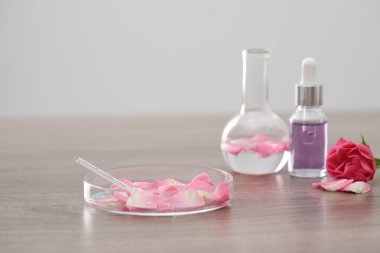 Lüks parfüm yapıyorum. Temel yağlar cam süslemede ve çiçekler açık ahşap masada, yakın plan