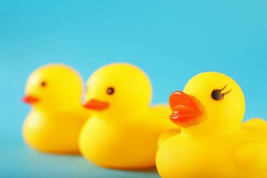 Açık mavi arkaplanda üç sevimli lastik ördek, yakın plan.