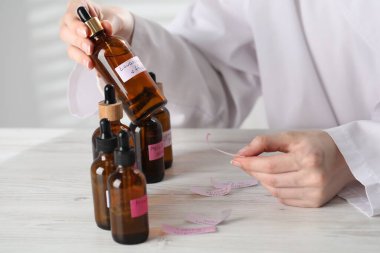 Laboratuvarda beyaz ahşap masada lüks parfüm üreten profesyonel bir parfümcü.