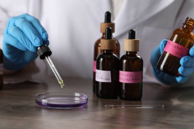 Laboratuardaki ahşap masada lüks parfüm üreten profesyonel parfümcü.