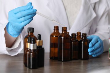 Laboratuardaki ahşap masada lüks parfüm üreten profesyonel parfümcü.