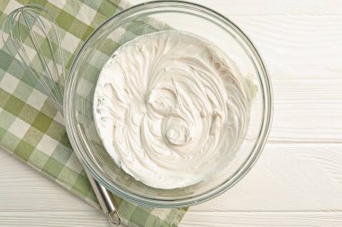 Krem şantili kase ve çırpılmış çırpılmış beyaz ahşap masa, üst manzara