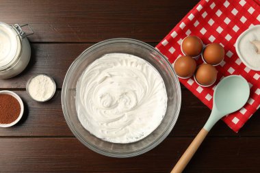 Krem şantili kase ve ahşap masa üzerinde malzemeler, düz yatıyordu.