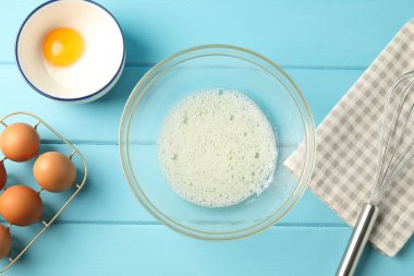 Krem şanti yapıyorum. Kase, çırpma ve malzeme açık mavi ahşap masa, düz uzanma