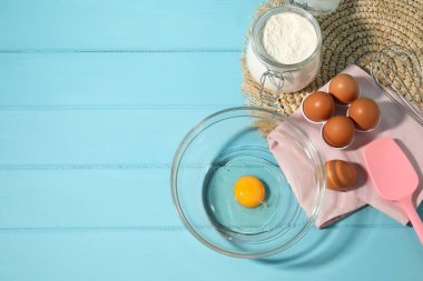 Krem şanti yapıyorum. Kase, çırpma ve malzemeler açık mavi ahşap masada, düz yerde. Metin için boşluk