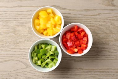 Taze renkli dolmalık biberler ahşap masadaki kaselerde, düz yatıyordu.