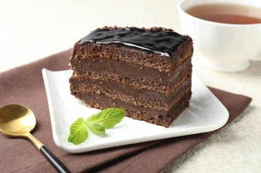 Nane, kaşık ve çayla servis edilen bir parça çikolatalı kek, yakın plan.