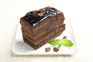 Bir parça çikolatalı kek, beyaz masada nane şekeri ile servis ediliyor, yakın plan.