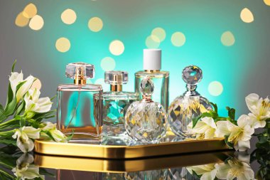 Ayna yüzeyinde birçok farklı parfüm şişesi ve çiçek bulanık ışıklı turkuaz arka planda, yakın plan