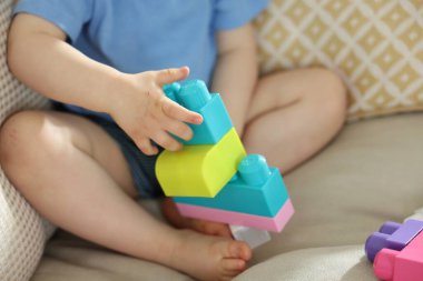 Evdeki kanepede tuğlalarla oynayan sevimli küçük çocuk, yakın plan.