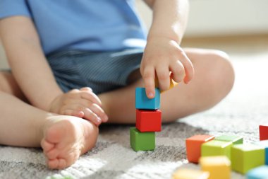 Evde renkli küplerle oynayan sevimli küçük çocuk, yakın plan.