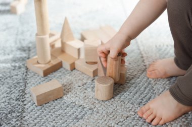 Evdeki ahşap yapı taşlarıyla oynayan sevimli küçük çocuk, yakın plan.