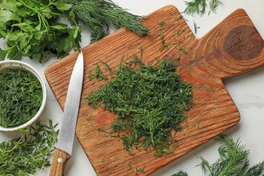 Farklı taze otlar ve beyaz mermer masa üzerinde bıçak, düz.