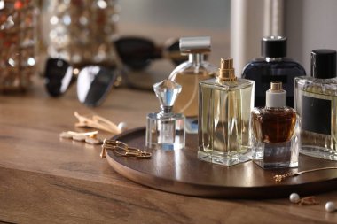 Ahşap masada farklı parfüm ve aksesuar şişeleri, yakın plan. Metin için boşluk