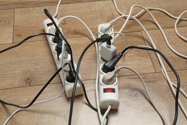 Uzatma güç panoları ahşap zemindeki tıkaçlarla aşırı yüklenmiş, yakın plan.