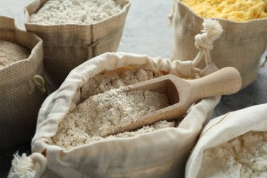 Gri desenli masa üzerinde farklı tipte un, yakın plan.