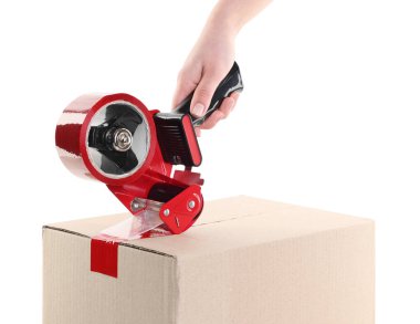 Kadın, beyaz arka plandaki karton kutuyu mühürlemek için yapışkan bantla yapıştırıcı kullanıyor.