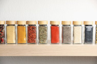 Kapalı alandaki ahşap raftaki kavanozlardaki farklı aromatik baharatlar.