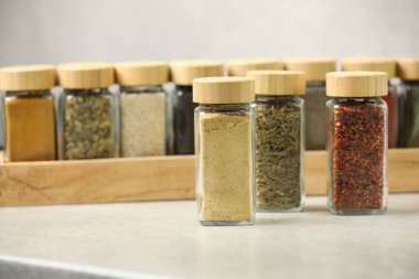 Açık gri masadaki kavanozlardaki farklı aromatik baharatlar.