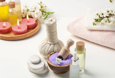 Spa ürünleri, güzel çiçekler ve beyaz masada yanan mumlar, yakın plan.