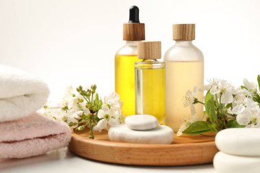 Spa ürünleri, çakıl taşları ve beyaz masadaki güzel çiçekli dallar, yakın plan.