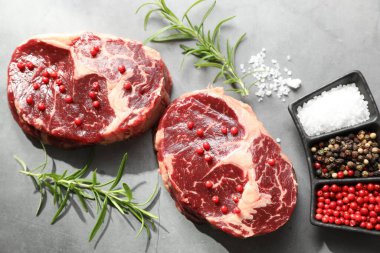 Çiğ et parçaları ve baharatlar gri dokulu masa üzerinde, düz yatıyordu.