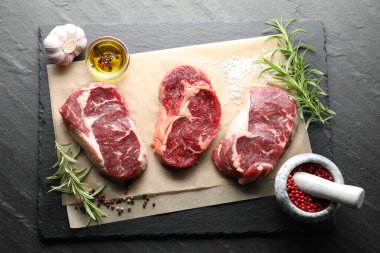 Çiğ et parçaları ve baharatlar siyah masanın üzerinde, düz yatıyordu.