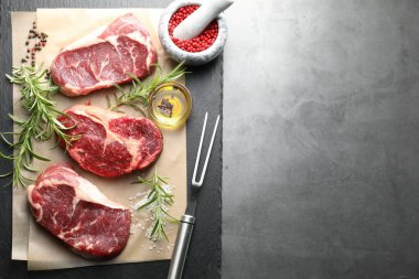 Çiğ et, baharat ve çatal parçaları gri masada, düz yerde. Metin için boşluk