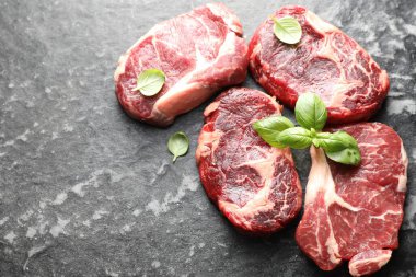 Koyu masa üzerinde çiğ et ve fesleğen parçaları. Metin için boşluk